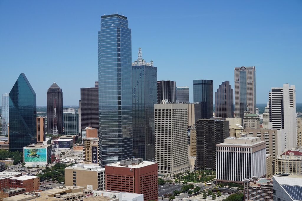 View of Dallas skyline with prominent skyscrapers, including the Bank of America Plaza and the Reunion Tower, under clear blue skies.