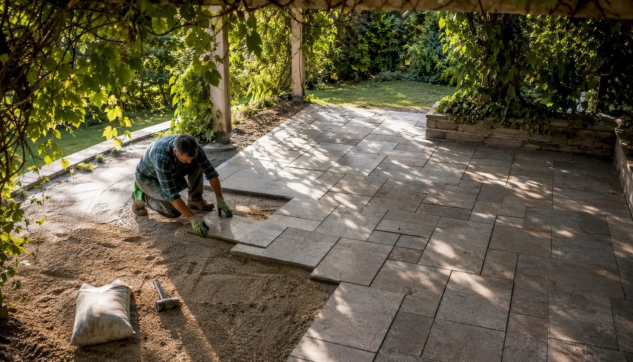 Hands installing herringbone paver driveway pattern