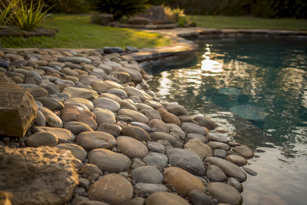 Smooth river rock by backyard pool for safe play