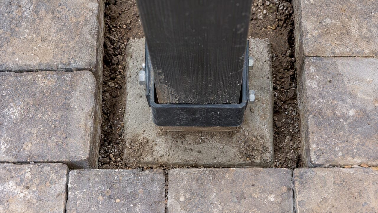 Metal standoff lifting pergola post above concrete footing